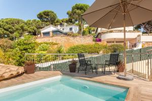 a swimming pool with chairs and an umbrella at Villa con Infinity pool in Lloret de Mar