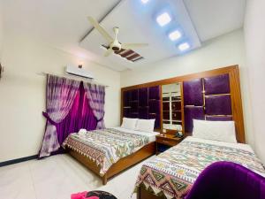 a bedroom with two beds and a ceiling fan at Travel Inn clifton in Karachi