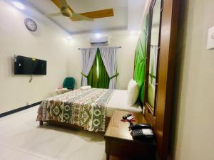 a hotel room with a bed and a tv at Travel Inn clifton in Karachi +7 photos