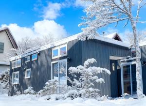 a house in the snow with snow covered trees at Lagom Hakuba in Hakuba