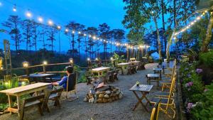 a woman sitting at tables in a garden at night at Hương Lúa Homestay Măng Đen in Kon Plong