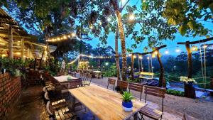 eine Terrasse mit einem Holztisch, Bänken und Lampen in der Unterkunft Hương Lúa Homestay Măng Đen in Kon Plong