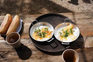 two frying pans with eggs and bread on a table at Hương Lúa Homestay Măng Đen in Kon Plong +37 photos