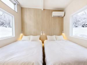 two beds in a small room with two windows at Lagom Hakuba in Hakuba