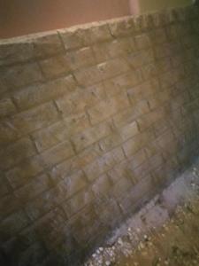 a brick wall next to a sidewalk withgrass at Pyramids in Ṭalkha