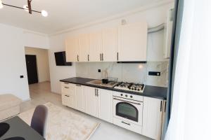 Una cocina con gabinetes blancos y un horno de estufa. en Cozy 2-Room Apartment - Free Parking - Close to Airport, en Apahida