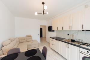 Una sala de estar con un sofá y una cocina. en Cozy 2-Room Apartment - Free Parking - Close to Airport, en Apahida