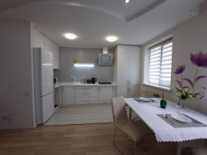eine weiße Küche mit einem Tisch und einem Kühlschrank in der Unterkunft 2 кімнатна квартира на Садовому in Shcherbani