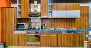 a kitchen with wooden cabinets and a sink and a microwave at VIP Apartment in Nizami street Downtown in Baku