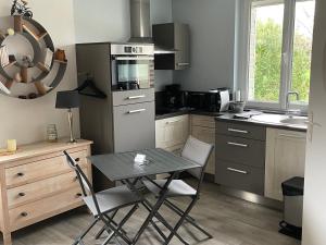 a kitchen with a table and chairs and a sink at Le cheval bleu in Larçay