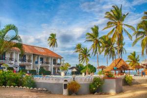 Un hotel en la playa con palmeras al fondo. en Protels La Plage, en Bwejuu