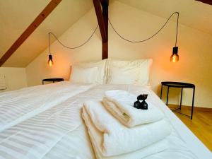 a white bed with towels and a black cat on it at -TheUrbanist- Sauna Free Parking Fast WiFi in Unterseen