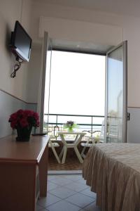 Habitación con balcón con mesa y TV. en Hotel Ideal, en Arma di Taggia
