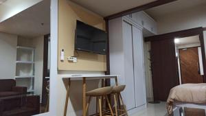 a room with a desk with a television and a bed at Ruby Apartment #29 in Yogyakarta