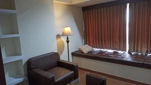 a room with a bed and a chair and a window at Ruby Apartment #29 in Yogyakarta