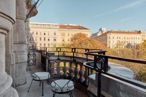 a balcony with two chairs and a bridge with buildings at Miiro Palais Rudolf in Vienna