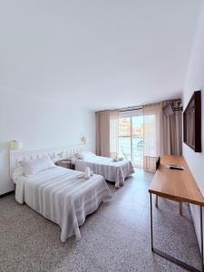 a bedroom with two beds and a table at L'Illa Hotel in Tossa de Mar +18 photos