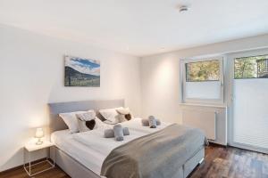 ein weißes Schlafzimmer mit einem Bett und zwei Fenstern in der Unterkunft Forest Apartment - Renchen in Unterberg