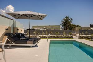 a patio with a pool and an umbrella and a couch and an umbrella at Ionian Treasure Suites in EFL