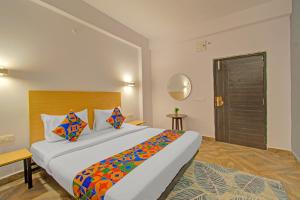 a hotel room with a large bed with colorful pillows at FabHotel The Vibe - Nr SR Nagar Metro Station in Hyderabad +28 photos