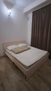 a bed sitting in a room with a window at Пишпек плюс in Bishkek