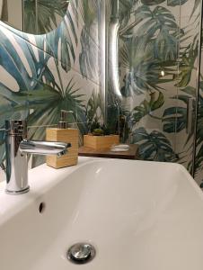 een badkamer met een witte wastafel met tropisch behang bij B&B Esotica in San Giovanni Teatino