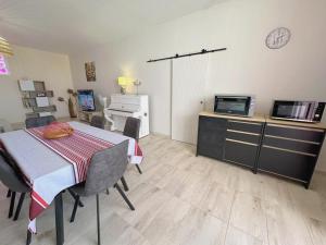 a room with a table and a kitchen with a microwave at Gite tafan in Pouillon