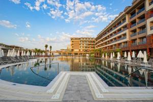a swimming pool in front of a building with chairs and umbrellas at Aletris Deluxe Hotel & SPA in Side