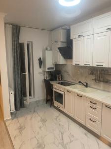 a kitchen with white cabinets and a marble floor at Apartament Premium Militari Parcare Self Check-in in Roşu