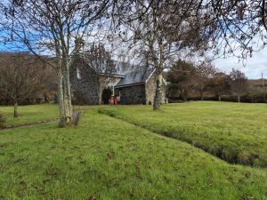 a stone house in a field with trees at Kilfinichen Church in Kilfinchen