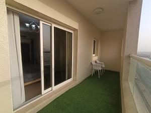a balcony with a large window and green carpet at ApartHotel Rooms in Ajman 
