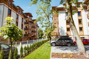 une voiture garée devant un immeuble dans l'établissement Rezydencja Park Rodzinna - FAF, à Mielno
