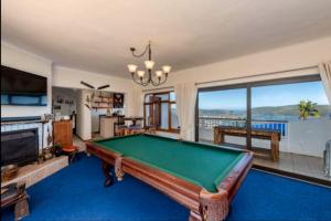 a living room with a pool table and a large window at Pamosoro Pegomo Villa - Luxurious Knysna Views! in Knysna