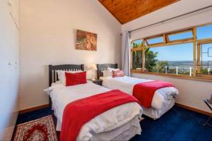 two beds in a room with a window at Pamosoro Pegomo Villa - Luxurious Knysna Views! in Knysna +23 photos