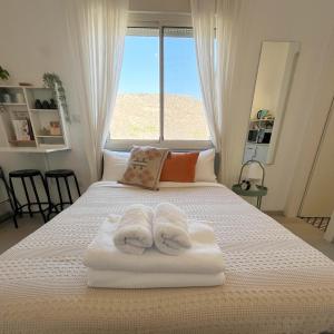 a bedroom with two towels on a bed with a window at ארץ מדבר - יחידת אירוח בבאר אורה in Beʼer Ora