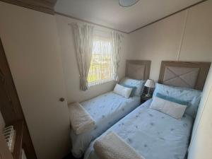 a small bedroom with two beds and a window at Skegness Retreats The Grange F59 in Ingoldmells