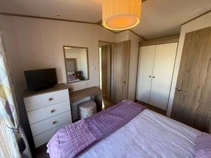 a bedroom with a bed and a dresser and a tv at Skegness Retreats The Grange F59 in Ingoldmells