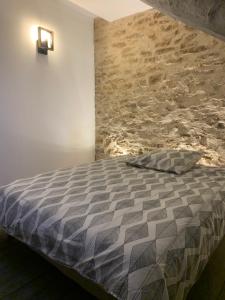 a bedroom with a bed with a stone wall at Le Numéro 2 in Ornans +1 photo