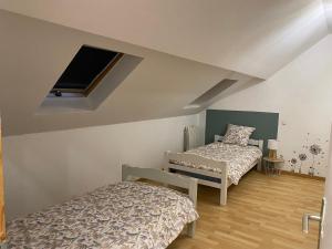 a bedroom with two beds and a tv on the wall at Le Numéro 2 in Ornans