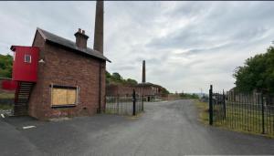 PatnaにあるThe Bunkhouseの煉瓦造りの建物と柵の空き道