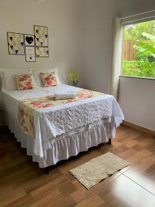 a bedroom with a bed with a white bedspread and a window at Casa às margens do Rio Caraíva, área verde in Caraíva