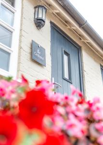 Un edificio con una puerta azul y flores rosas. en Wheatsheaf Inn, Bar Hill, en Onneley