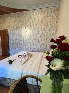 una stanza con tavolo e vaso di rose di Sapo Guest House a Berastagi