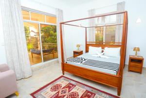 a bedroom with a canopy bed and a balcony at Menai Bay Escape in Mkunguni