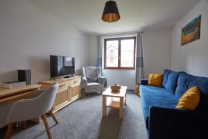 a living room with a blue couch and a tv at Rezort Gothal Apartmány a Penzióny in Donovaly