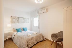 a bedroom with a bed with blue pillows and a chair at En el Corazón de Sevilla in Seville