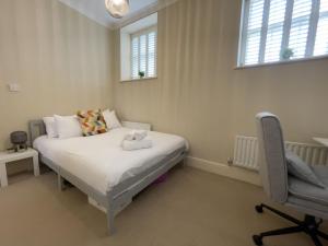 ein Schlafzimmer mit einem Bett und einem Stuhl und Fenstern in der Unterkunft The Manor Retreat in Oxford