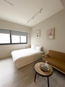 een slaapkamer met een bed, een tafel en een bank bij meimo文旅 in Taichung