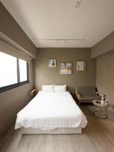 een slaapkamer met een groot wit bed en een stoel bij meimo文旅 in Taichung +27 foto's