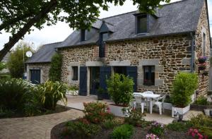 een oud stenen huis met een patio en bloemen bij Maison Les Volets Bleus Binic in Lantic